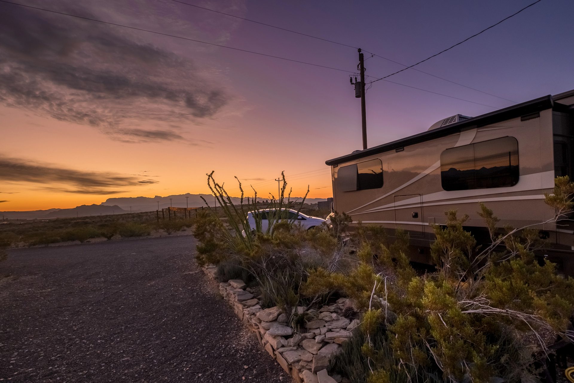 An RV camped in the West Texas desert near Terlingua at sunset, under a dramatic sky